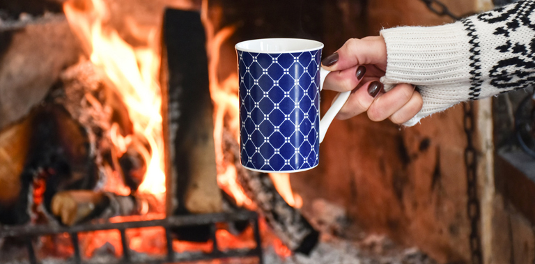 Holding drink in front of fireplace